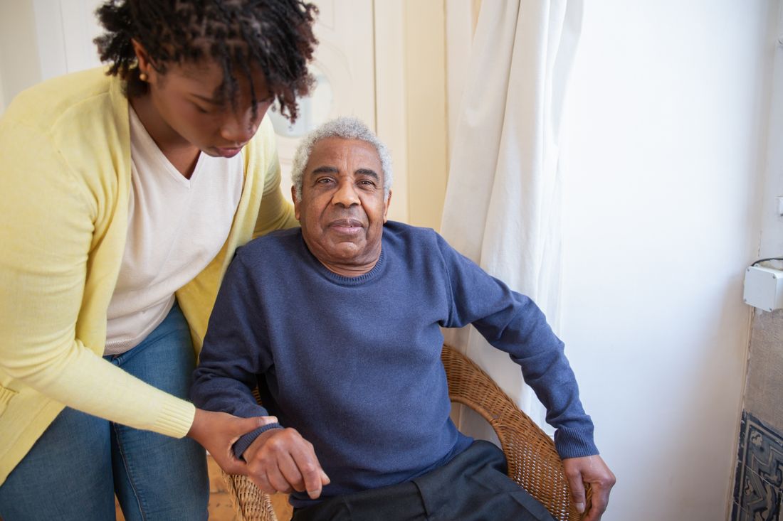 A support worker sitting beside an older man in his living room
